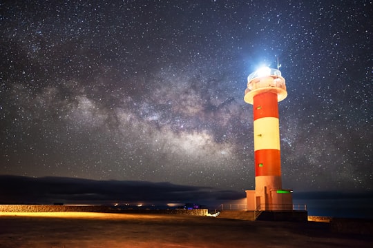 red and white striped lighthouse lighted near shore in La Palma Spain