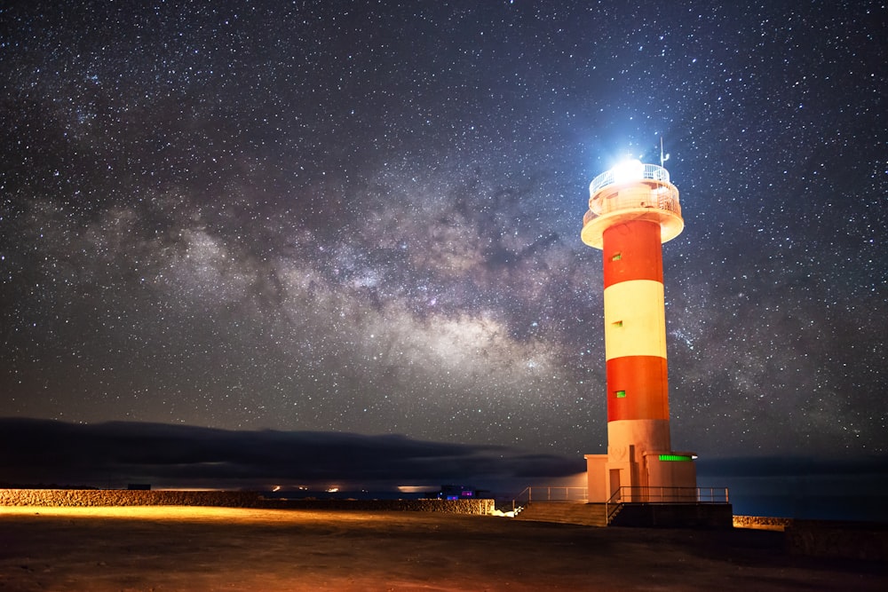 red and white striped lighthouse lighted near shore