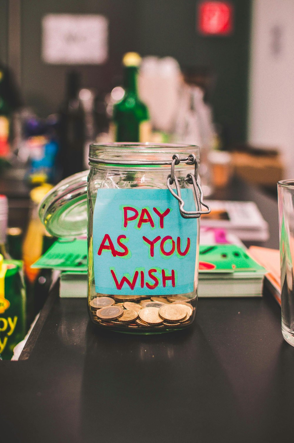 clear glass mason jar with pay as you order sticker filled with coins