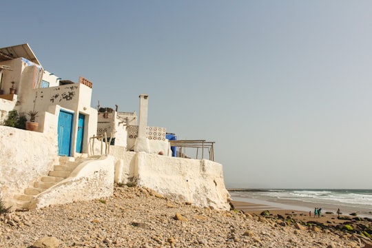 white concrete building near beach during daytime in Imsouane Morocco