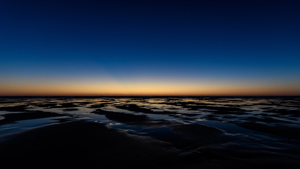 the sun is setting over the water at the beach