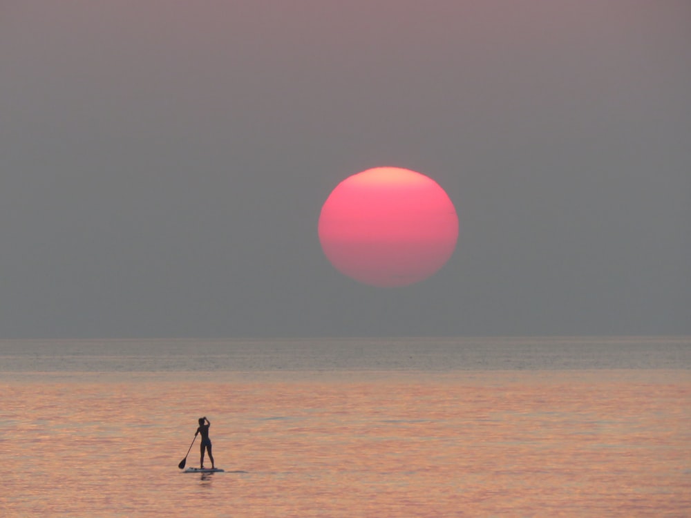 person riding on surfboard during golden hour