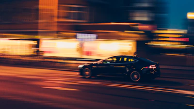A mach1 vehicle speeding through an urban nightscape, lights blurring in motion.