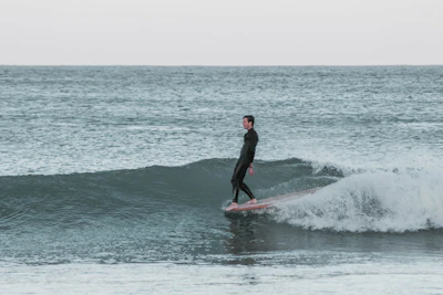 A beginner standing up on the surfboard for the first time with waves gently rolling in