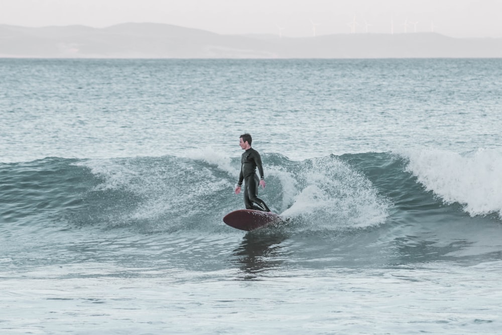 man in black wet suit surfing