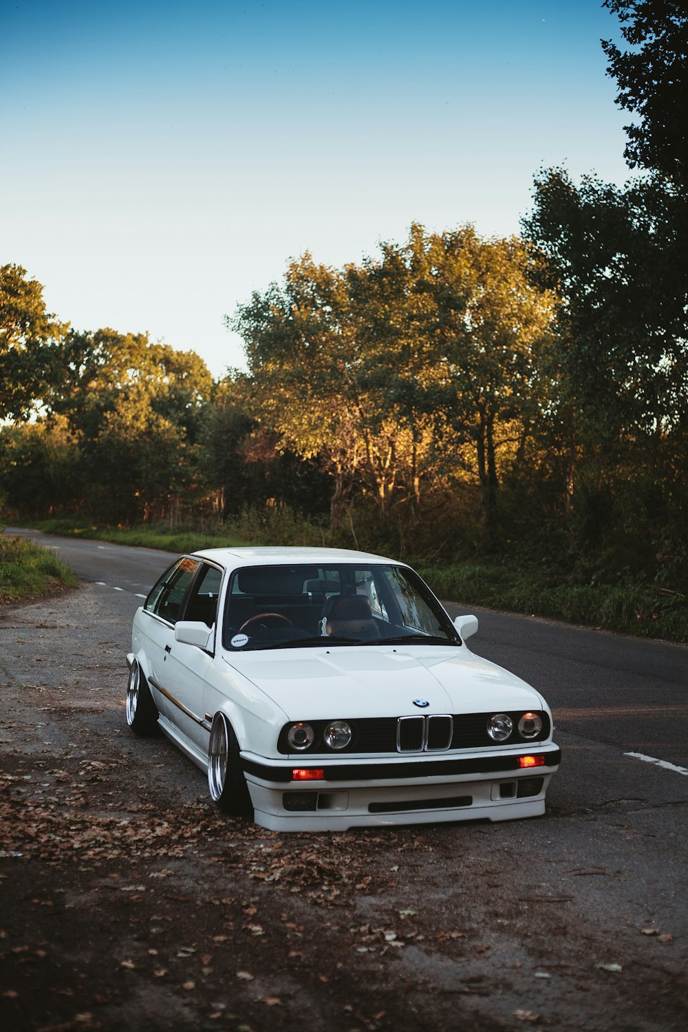 white BMW sedan on black asphalt road during daytime