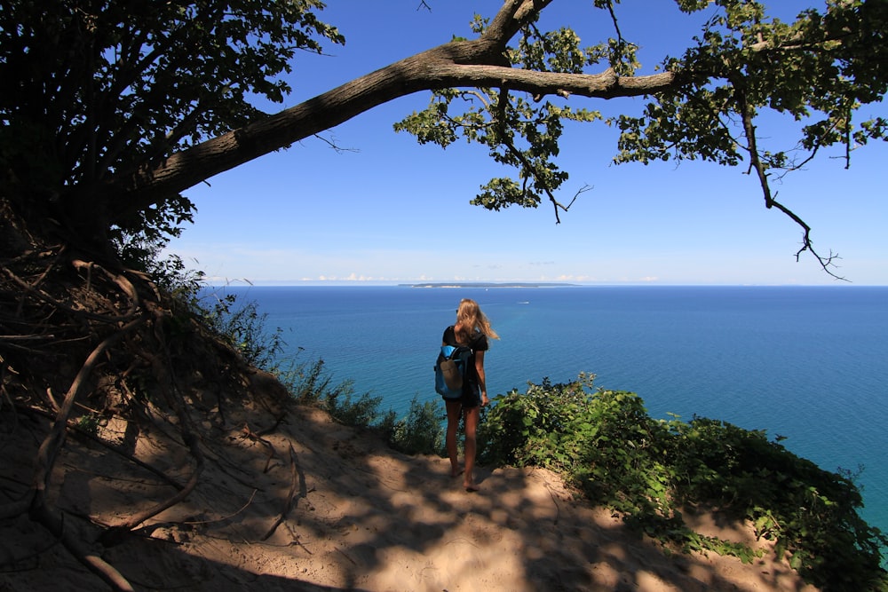 a woman standing on top of a cliff next to the ocean