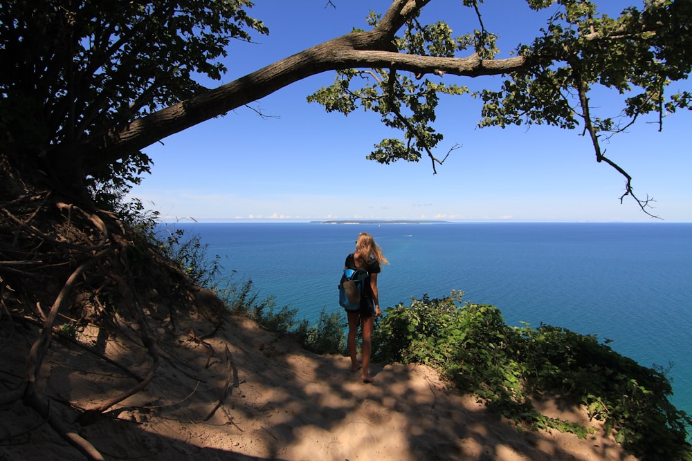 海の隣の崖の上に立つ女性