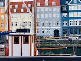 A stylish wooden sailboat docked at a marina with Lisbon’s historic buildings in the background.