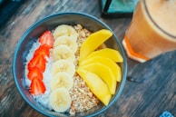 Fresh fruits and a smoothie bowl arranged on a bright kitchen table, symbolizing healthy habits.