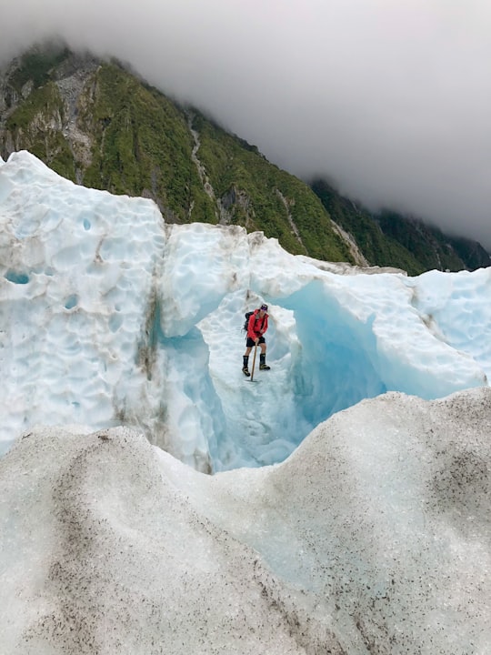 person standing on ice hill in Franz Josef Glacier New Zealand