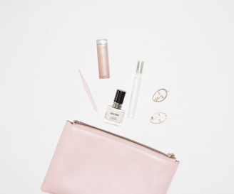 white nail polish bottle and pink leather zip pouch