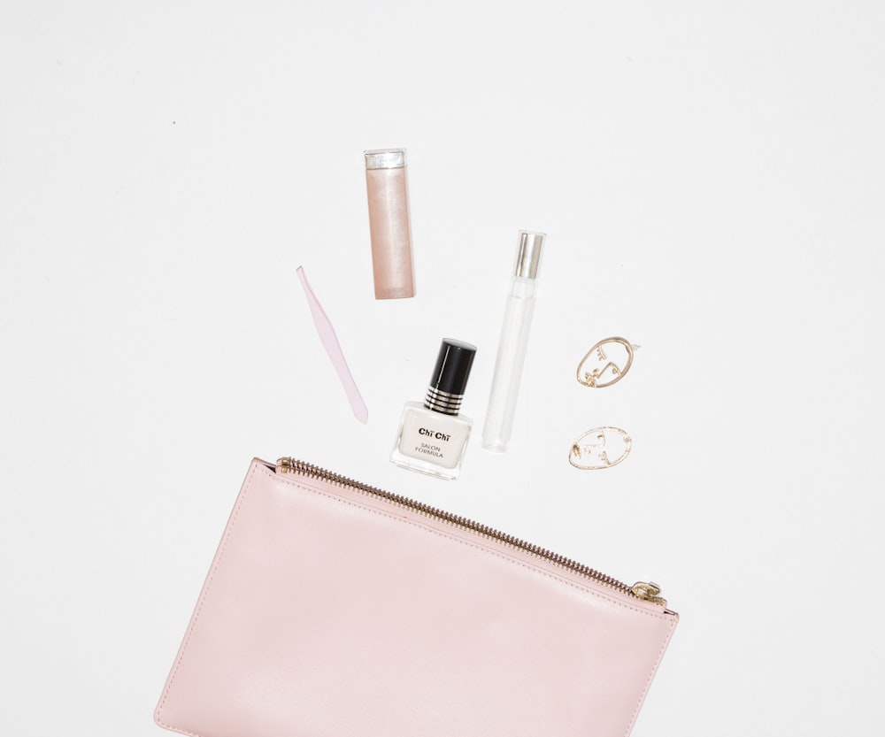 white nail polish bottle and pink leather zip pouch