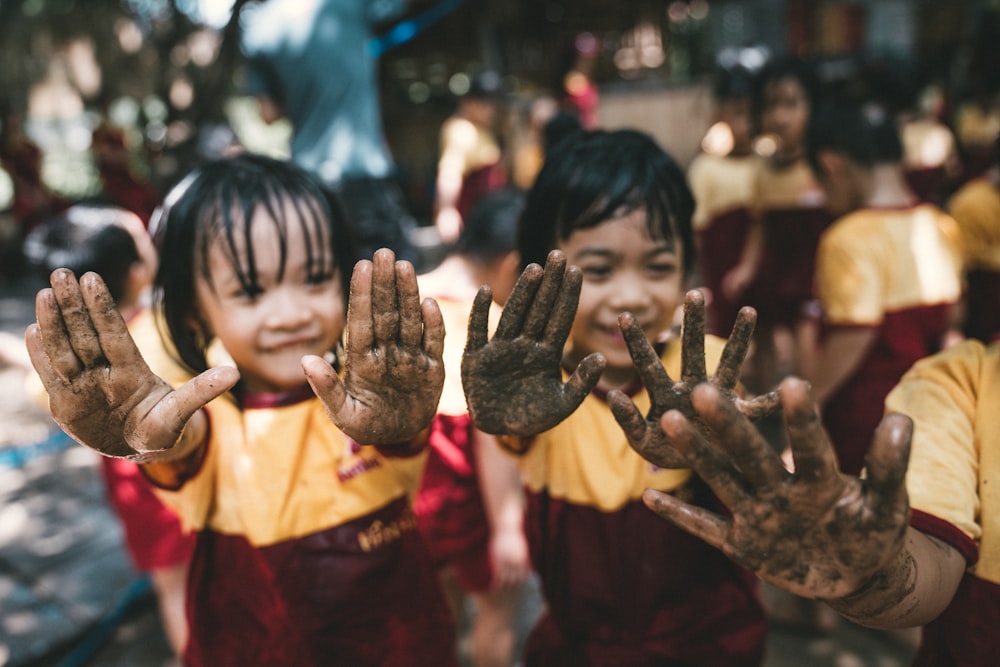 two girls showing their hands with black sands