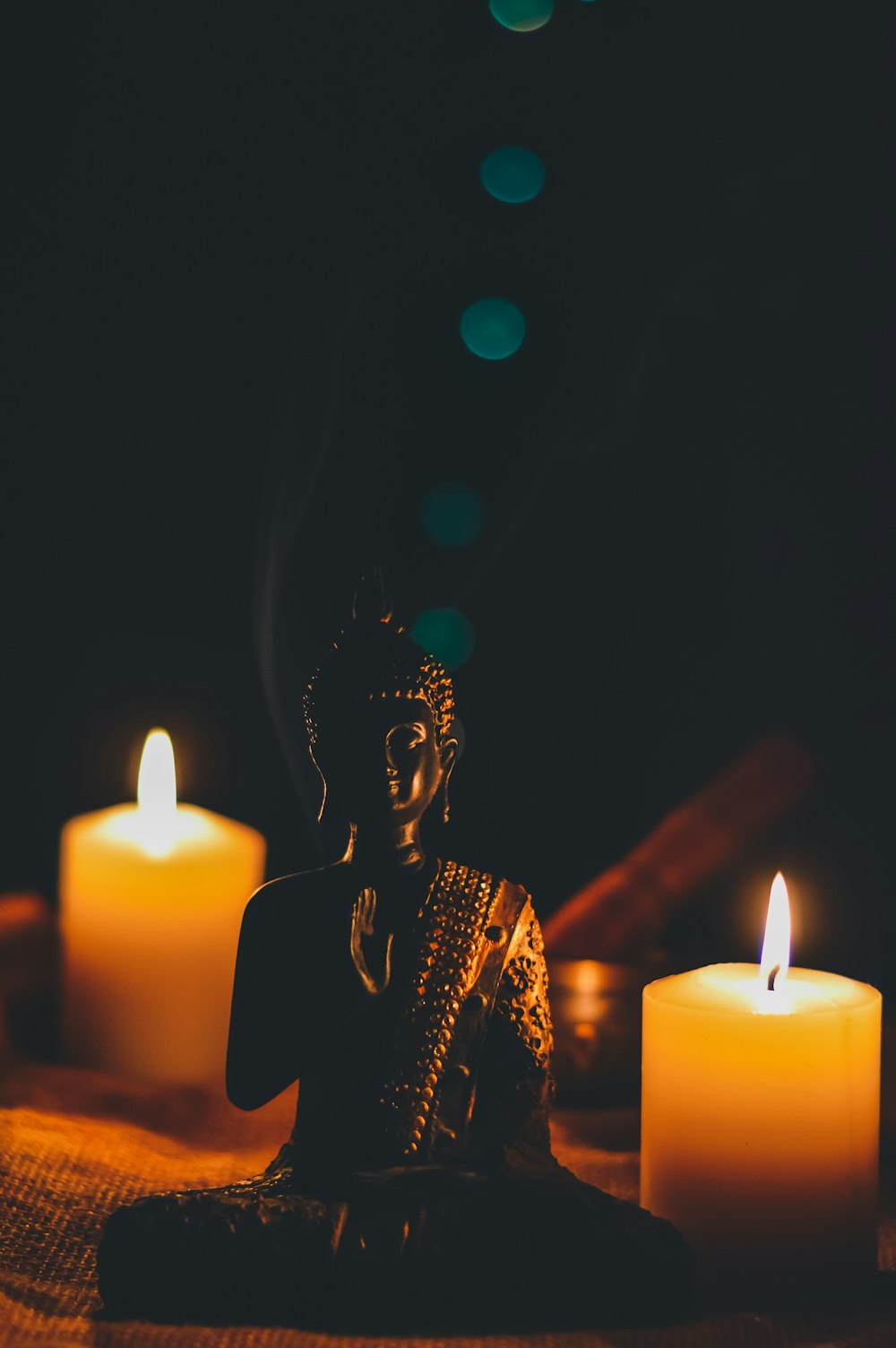 柱の蝋燭のそばに座っている仏陀