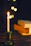 A softly lit candle glowing beside a stack of well-loved books on a wooden table.