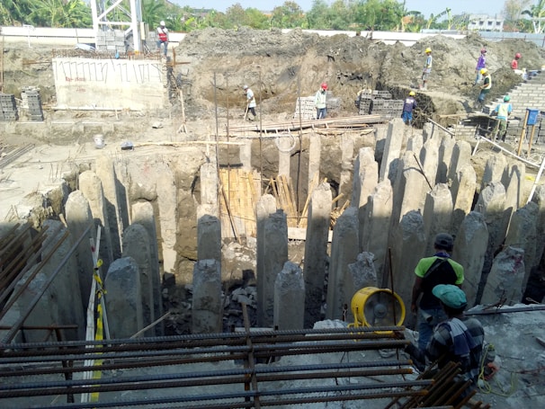 Close-up of reinforced concrete foundation work with Korean safety banners and engineers in traditional helmets.