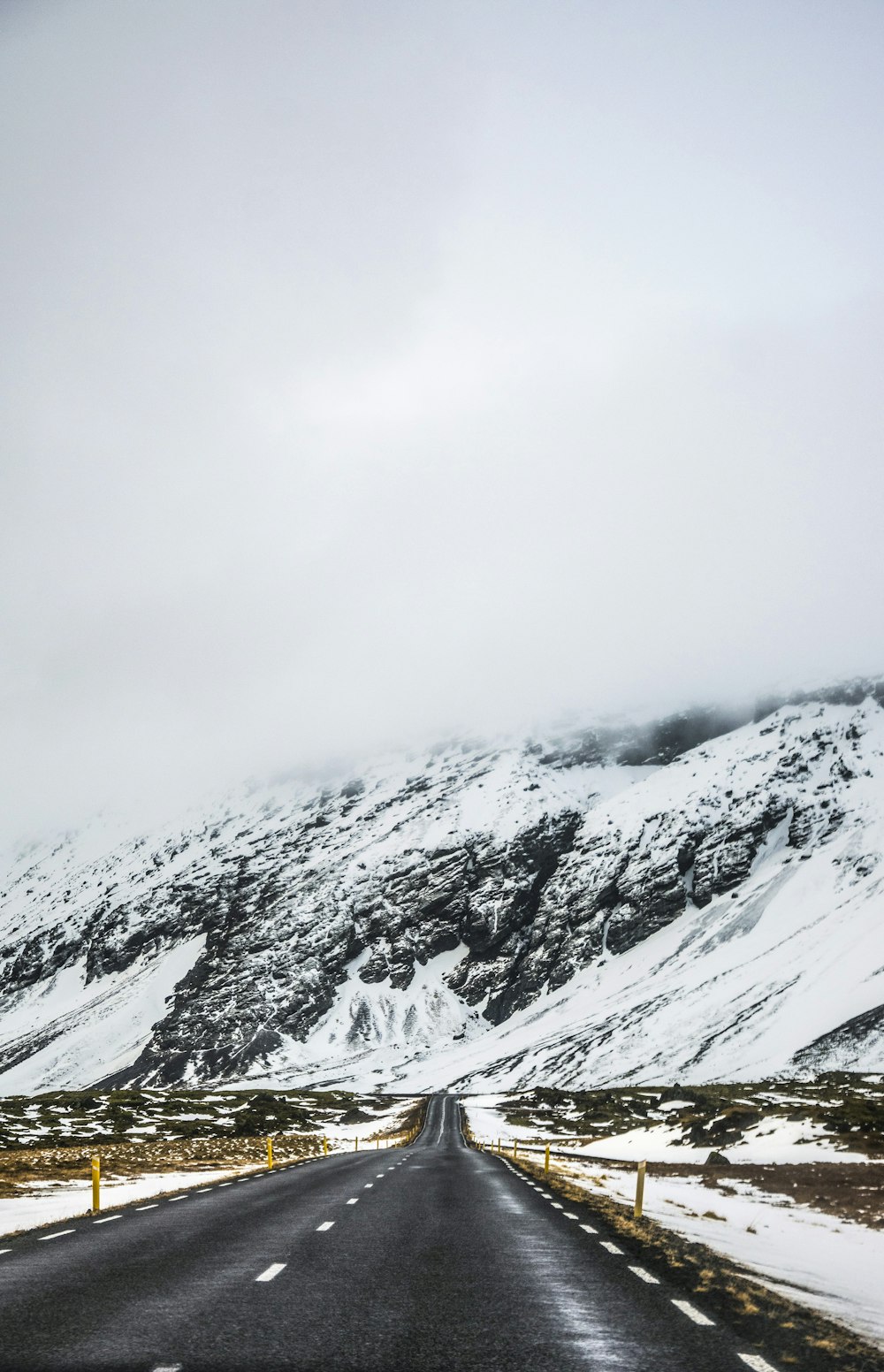 Estrada vazia ao lado da montanha coberta de neve