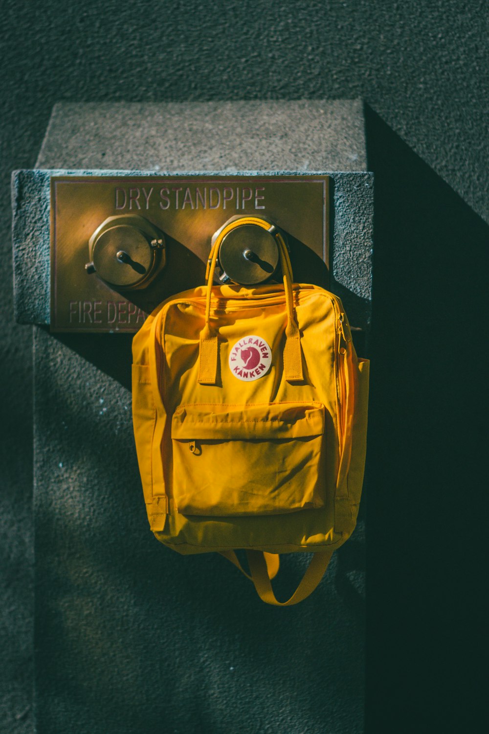 yellow backpack hanging on brown wall leg shelf