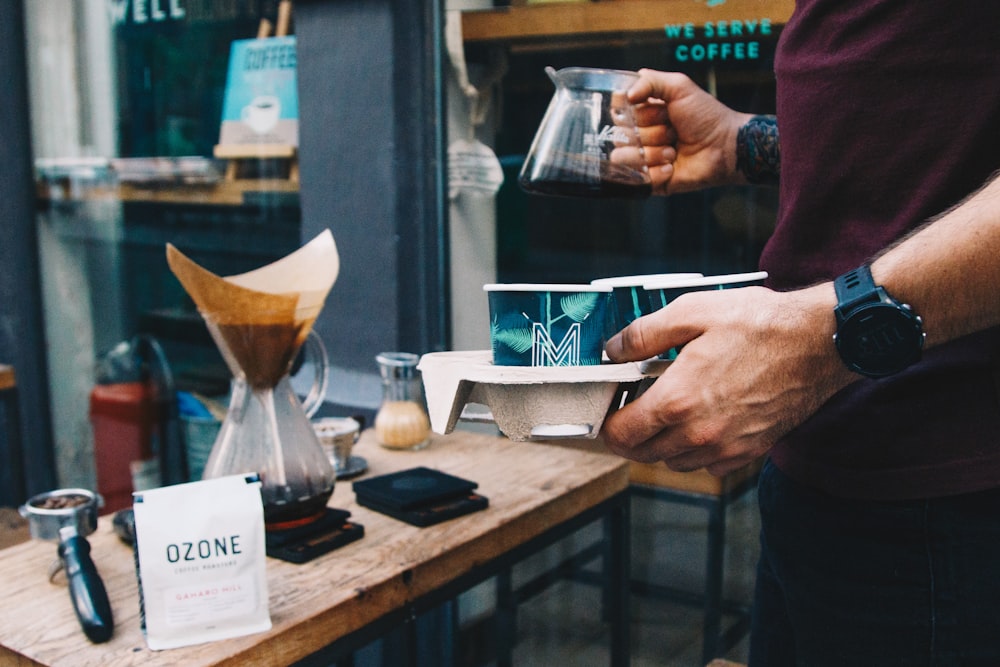 person holding glass teapot with black liquid