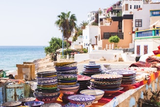 A serene coastal scene featuring artisan-crafted mugs and bowls on a wooden table.