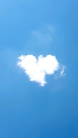 A cloud shaped like a heart against a bright blue sky.