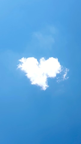 A cloud shaped like a heart against a bright blue sky.