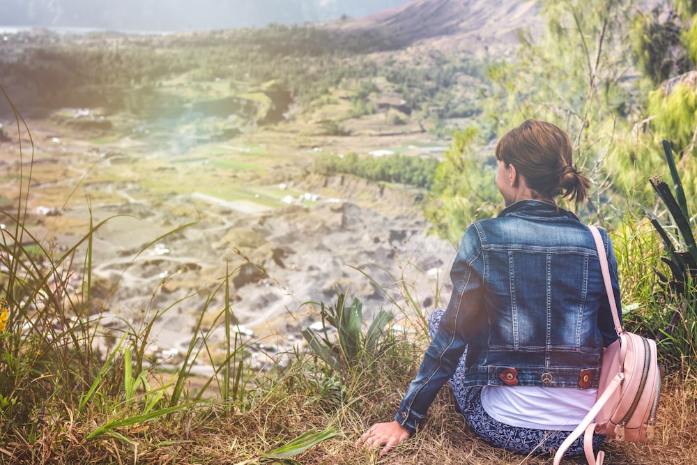 woman sitting on grass locking mountains