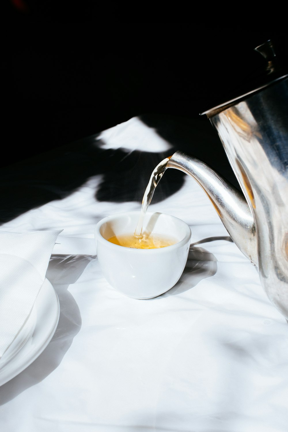 white ceramic cup pouring teapot