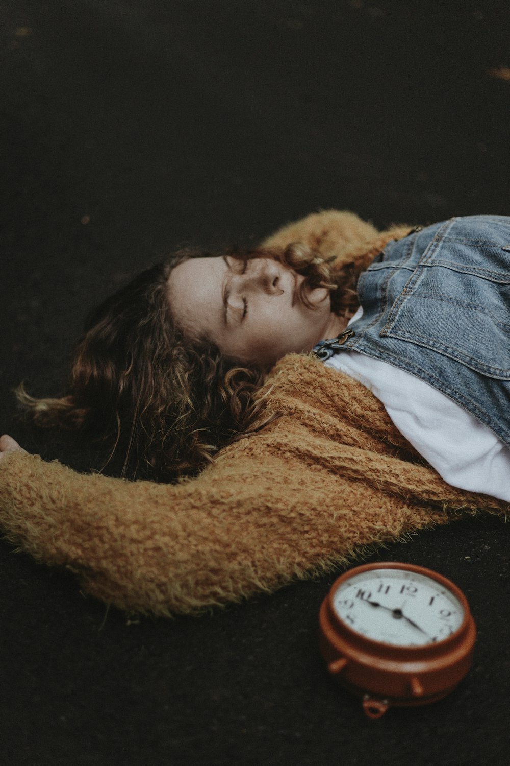 woman lying on floor near alarm clock