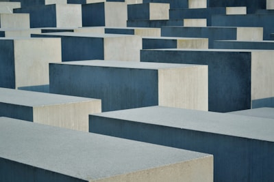 Large, rectangular concrete blocks of varying heights are arranged in a grid-like pattern. The blocks are shades of gray and are neatly aligned, creating a sense of uniformity and repetition.