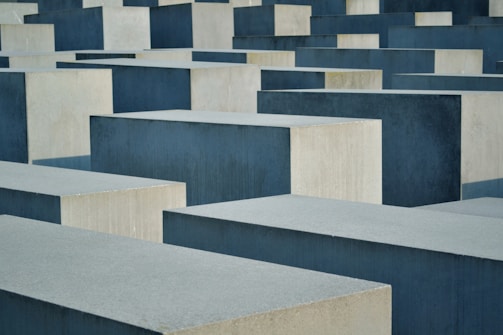 Large, rectangular concrete blocks of varying heights are arranged in a grid-like pattern. The blocks are shades of gray and are neatly aligned, creating a sense of uniformity and repetition.