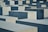 Large, rectangular concrete blocks of varying heights are arranged in a grid-like pattern. The blocks are shades of gray and are neatly aligned, creating a sense of uniformity and repetition.