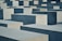 Large, rectangular concrete blocks of varying heights are arranged in a grid-like pattern. The blocks are shades of gray and are neatly aligned, creating a sense of uniformity and repetition.