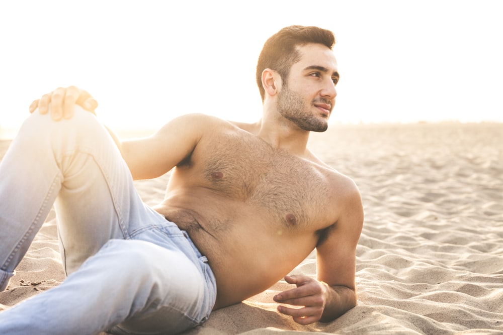 man lying while doing modeling pose at sand