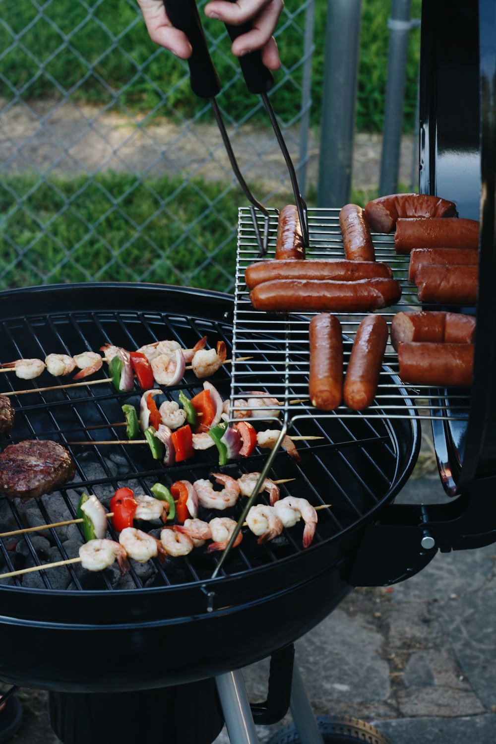 grilled sausage and meat beside gray chain-link fence
