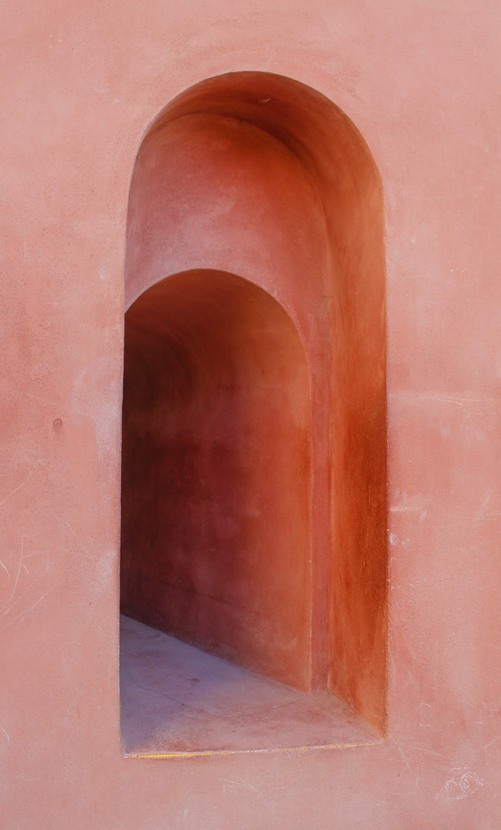 Una pared rosa con un túnel en el medio