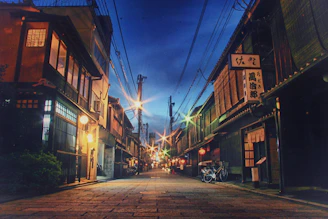 A cinematic shot of a quiet Tokyo street at dusk, with warm lights glowing and subtle hints of traditional and modern Japan blending.