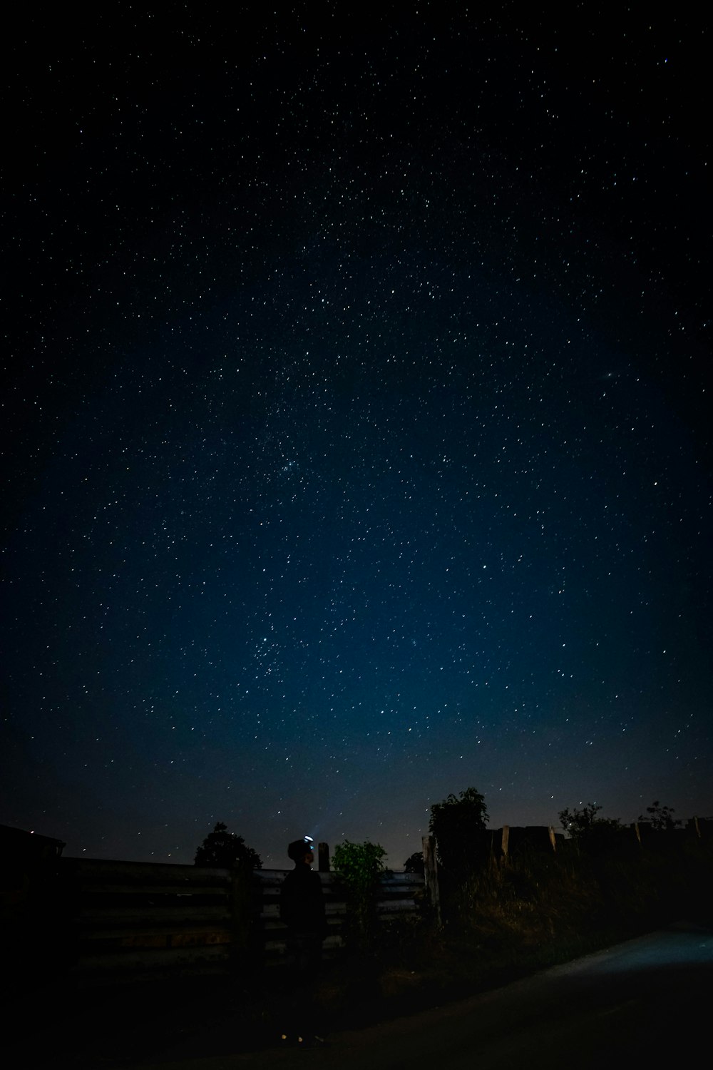 man standing near fence watching stars during night time