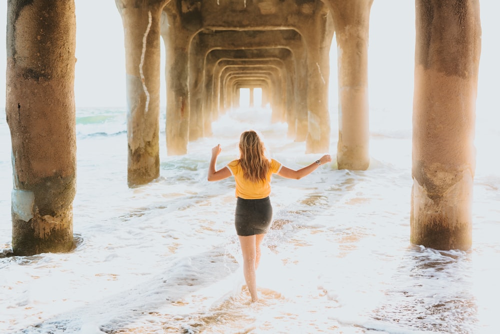 woman wearing yellow and black dress walking under sea dock