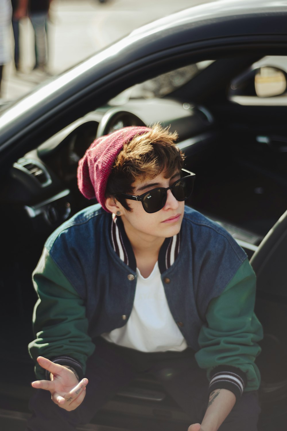 man wearing bomber jacket sitting on open door