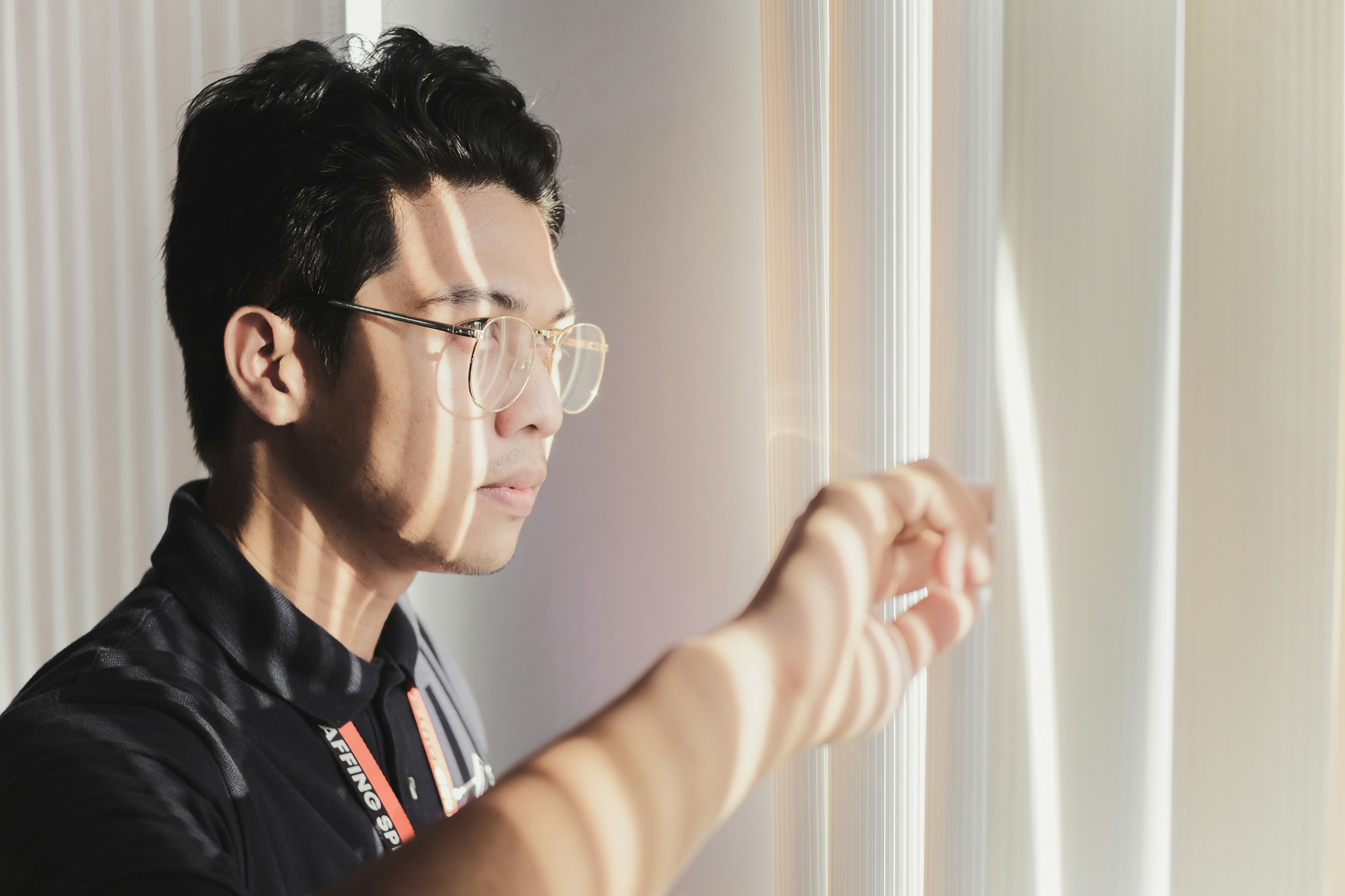 man peeking through window blinds