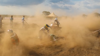 Wide shot of a group of racers launching off a dirt ramp under a moody, overcast sky.