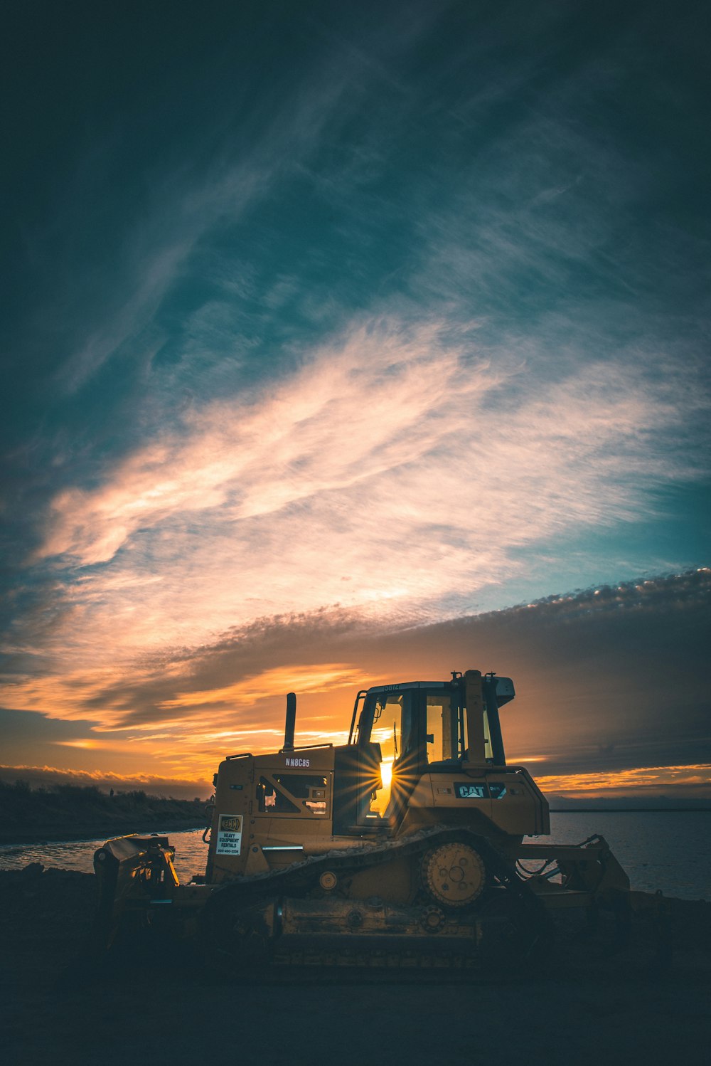 brown front-end loader on dirt near body of water