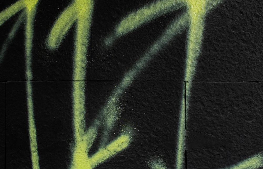 a black wall with yellow graffiti on it