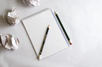 An open notebook filled with creative AI prompt ideas and colorful pens scattered around.