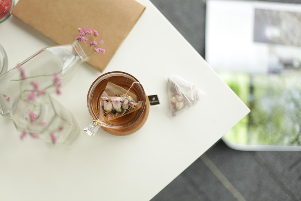 a table topped with a cup of tea next to a vase filled with flowers