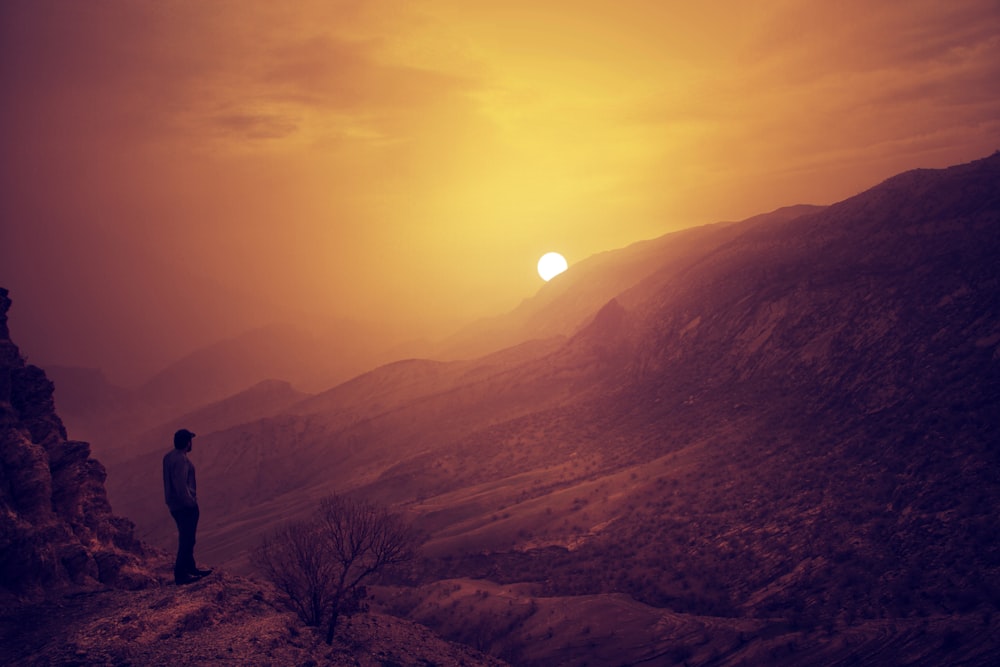 man standing on cliff during golden hour
