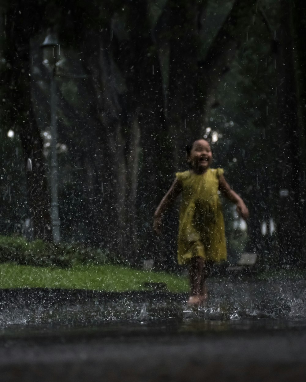 girl wearing yellow dress playing in the rain