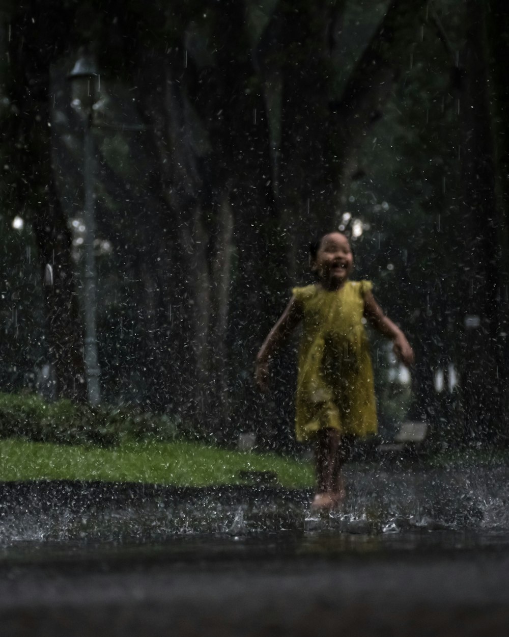Mädchen im gelben Kleid spielt im Regen